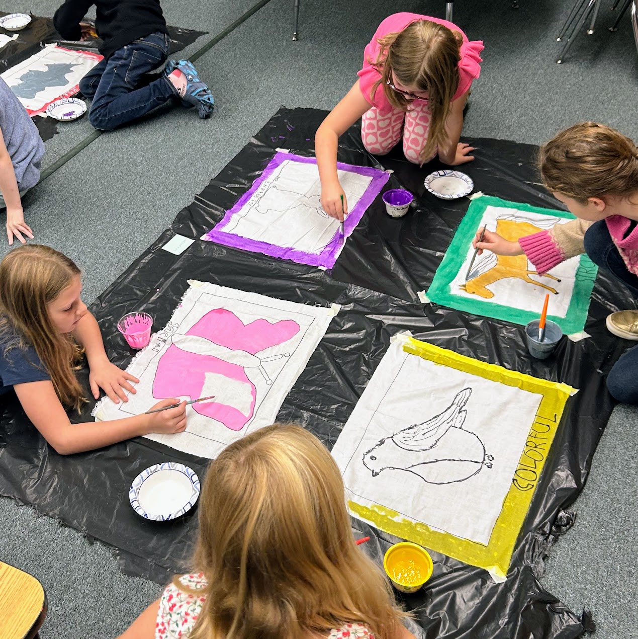 Students paint banners with animals on them. 